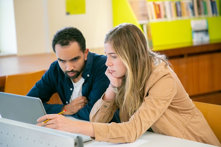 Classmates using laptop for studies while doing homework assignment together in university