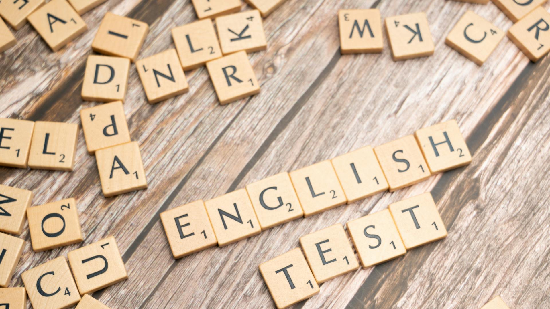 Wooden Scrabble tiles spelling out 'English Test' on a wooden background, ideal for language exam themes.