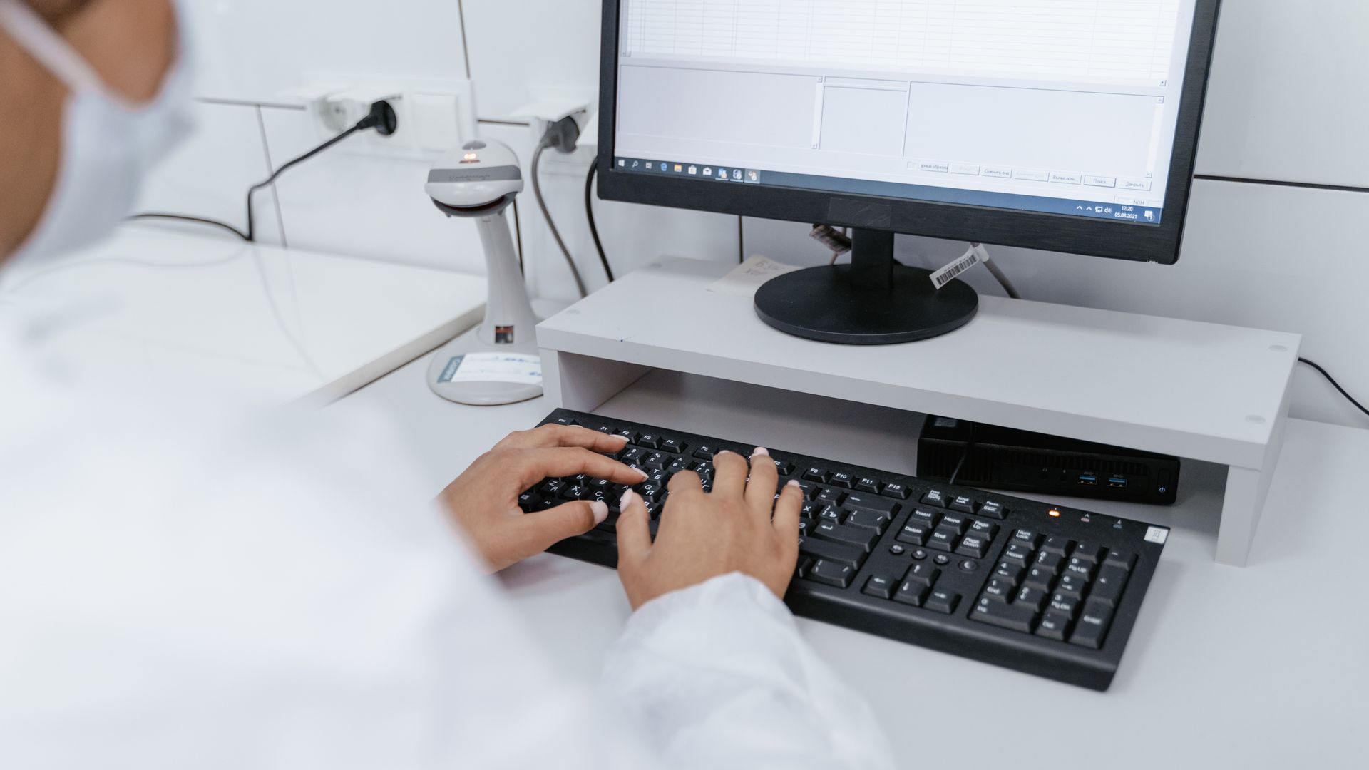 Scientist in white coat using a computer in a laboratory setting, focusing on data analysis.